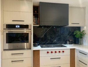 Contemporary two-tone kitchen featuring white and grey custom cabinets with dramatic black marble backsplash and wood trim by Polymita Woodcraft