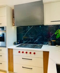 Contemporary two-tone kitchen featuring white and grey custom cabinets with dramatic black marble backsplash and wood trim by Polymita Woodcraft