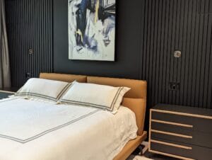 Dramatic modern bedroom featuring black vertical slat accent wall with custom black and wood dresser by Polymita Woodcraft