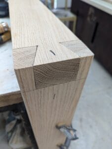 Detailed shot showing the tight fit and precision of a handcrafted, exposed dovetail joint in a wooden table leg.